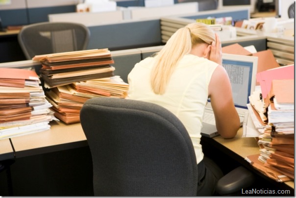 Businesswoman in cubicle with laptop and stacks of files