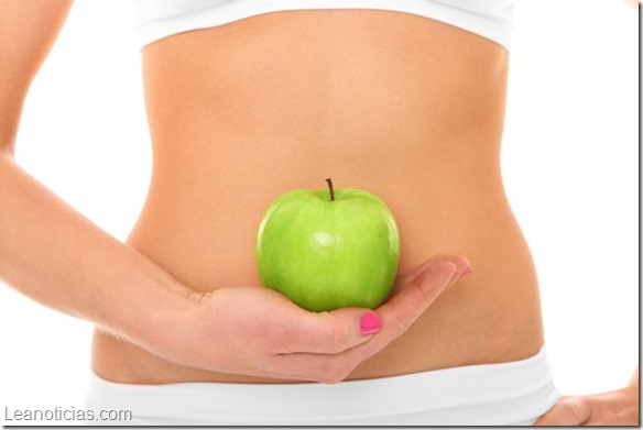 A picture of a woman holding a green apple in front of her fit belly