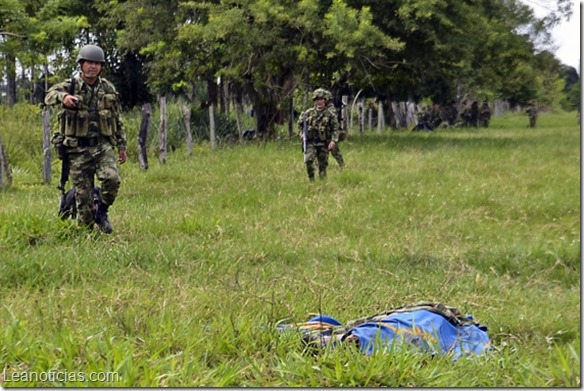 Colombian soldiers walk near the corpse of a soldier killed by members of the Revolutionary Armed Forces of Colombia (FARC) during a an attack in Tame, Arauca department, Colombia on July 21, 2013. Fifteen Colombian soldiers have been killed in an ambush by leftist FARC rebels, Colombian President Juan Manuel santos said Sunday, raising concerns about peace talks launched last year. AFP PHOTO/Daniel Martinez