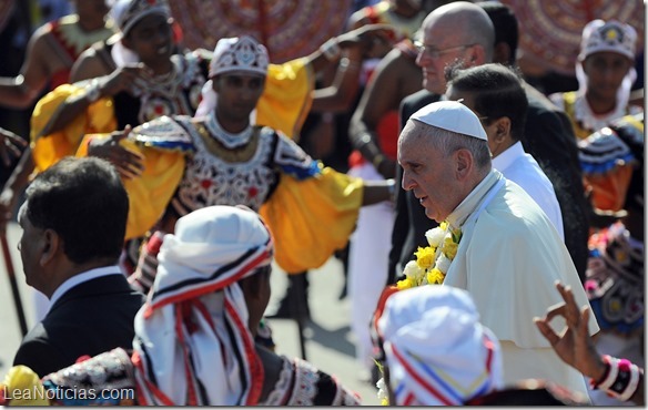 Pope Francis (R) walks during a welcoming ceremony as traditional dancers (background) perform during his arrival at the Bandaranaike International Airport in Katunayake on January 13, 2015. Pope Francis urged respect for human rights in Sri Lanka as he began a two-nation Asia tour on the island, bearing a message of peace and reconciliation after a long civil war. AFP PHOTO / ISHARA S. KODIKARA
