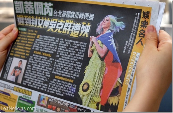 In this photo illustration taken on April 30, 2015, a local resident reads a newspaper showing US singer Katy Perry wearing Taiwan's national flag in Taipei. The intricacies of the "one China" policy may not have been uppermost on her mind, but US pop star Katy Perry caused a stir in Asia this week with her politically-charged choice of dress at a Taipei concert.  AFP PHOTO / Sam Yeh