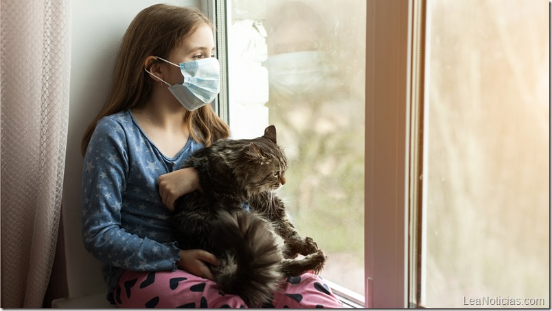 girl in medical mask holding cat and suffering from allergy at home
