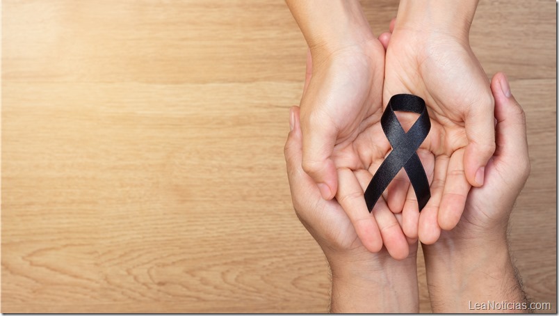Man hands holding a black ribbon on wooden background