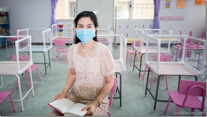 Asian female teachers wear medical masks, social distancing in classrooms and schools that are about to begin. There are plastic sheets between students studying together.